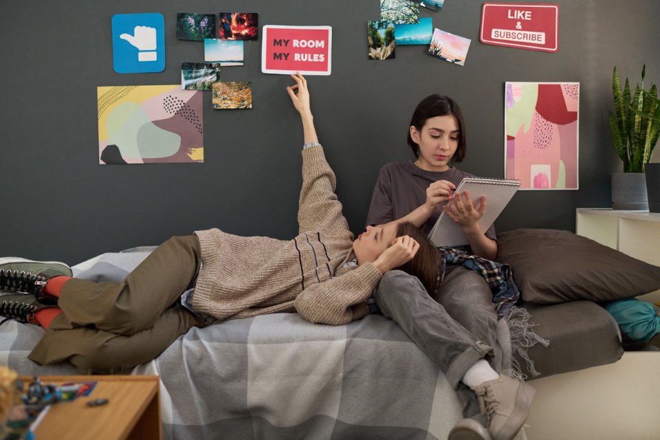 Due studenti universitari sdraiati sul letto nella loro stanza del dormitorio.