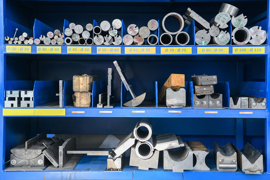 Organised storage of metal and industrial components on blue shelving.
