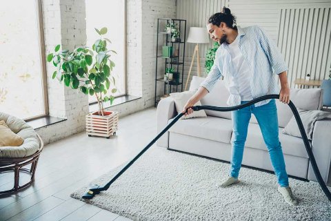 Uomo che passa l'aspirapolvere su un tappeto chiaro
