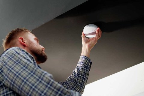 Uomo che installa un rilevatore di fumo sul soffitto