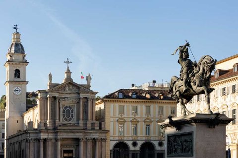 Piazza storica di Torino con statua e chiesa al tramonto
